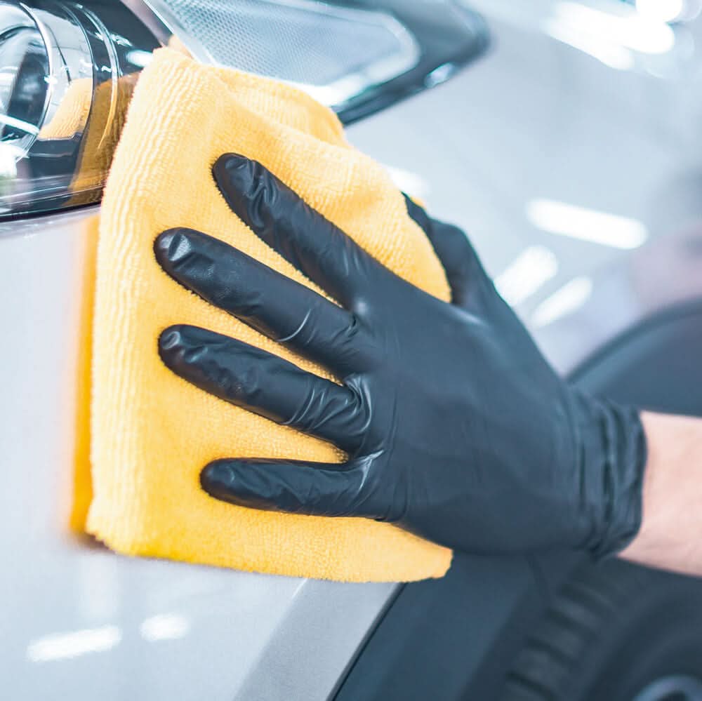 Hand reinigt Fahrzeug mit gelbem Tuch, trägt Hygonorm "Safe Fit" Nitril-Handschuhe Schwarz 200 Stück von Franz Mensch