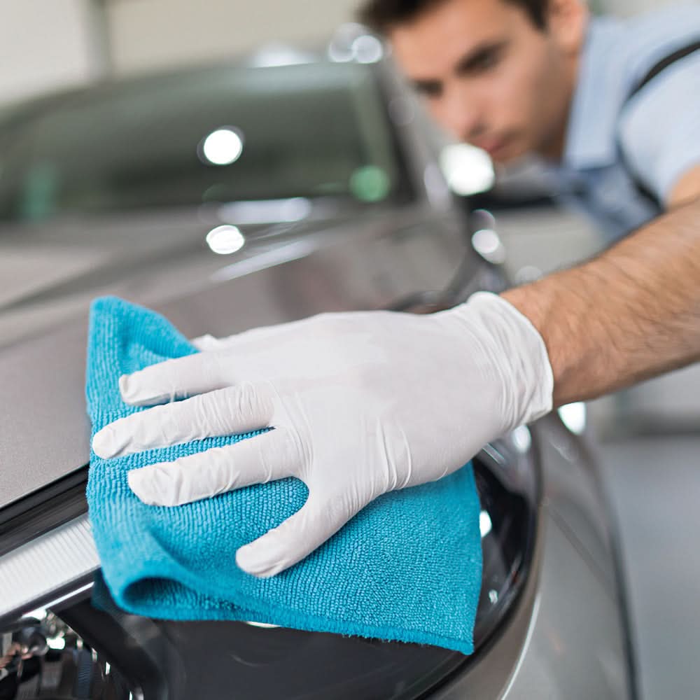 Mann reinigt Auto mit blauer Cloth und trägt Hygonorm "Safe Fit" Nitril-Handschuhe Weiß 100 Stück von Franz Mensch.