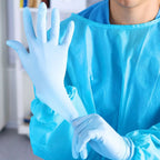 Person in chirurgischer kleidung trägt hellblaue hygienstar nitril-handschuhe safe super stretch aus 100 stück