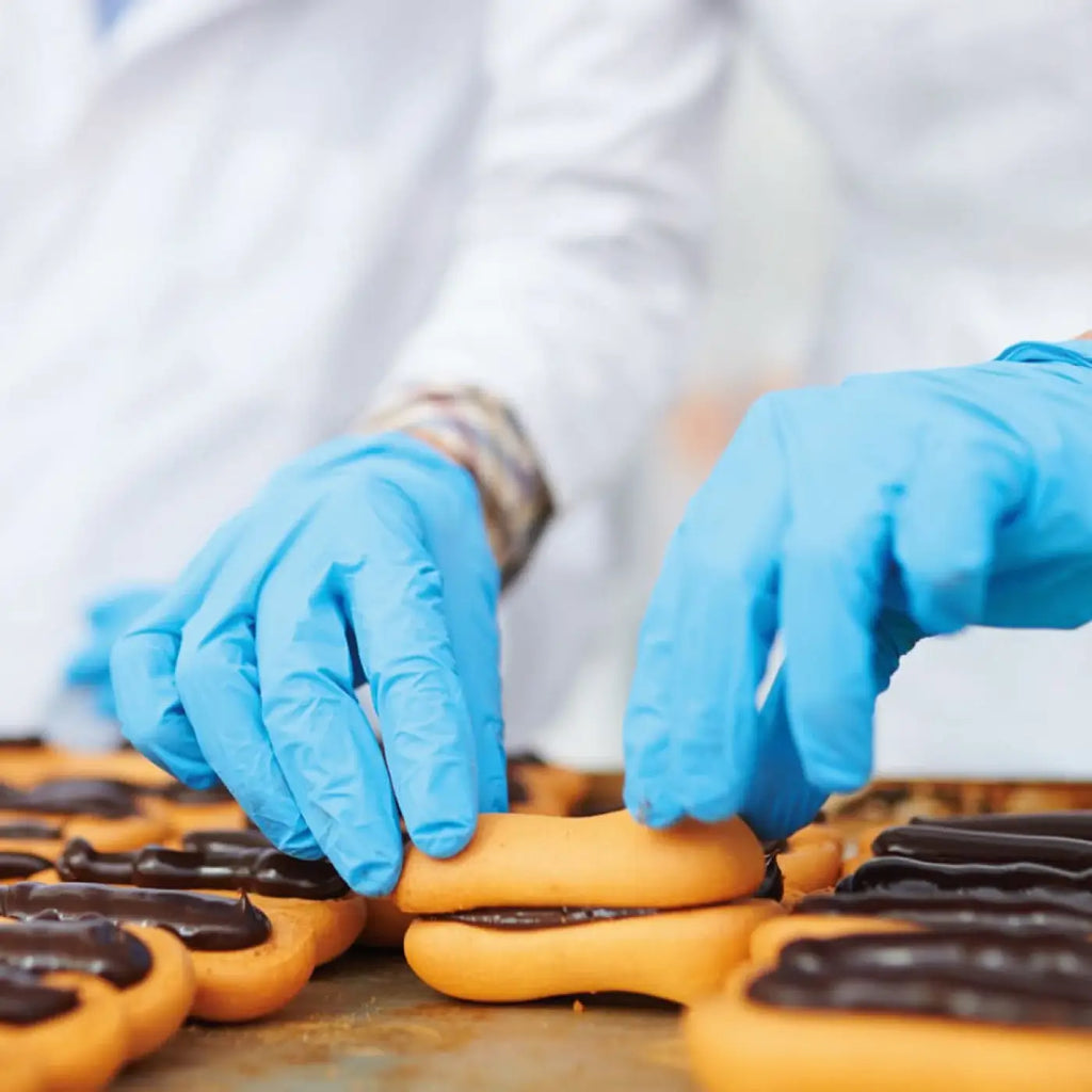 HygoStar nitrilhandschuhe extra safe blau puderfrei werden zum handling von goldbraunen schokogefüllten gebäckstücken verwendet
