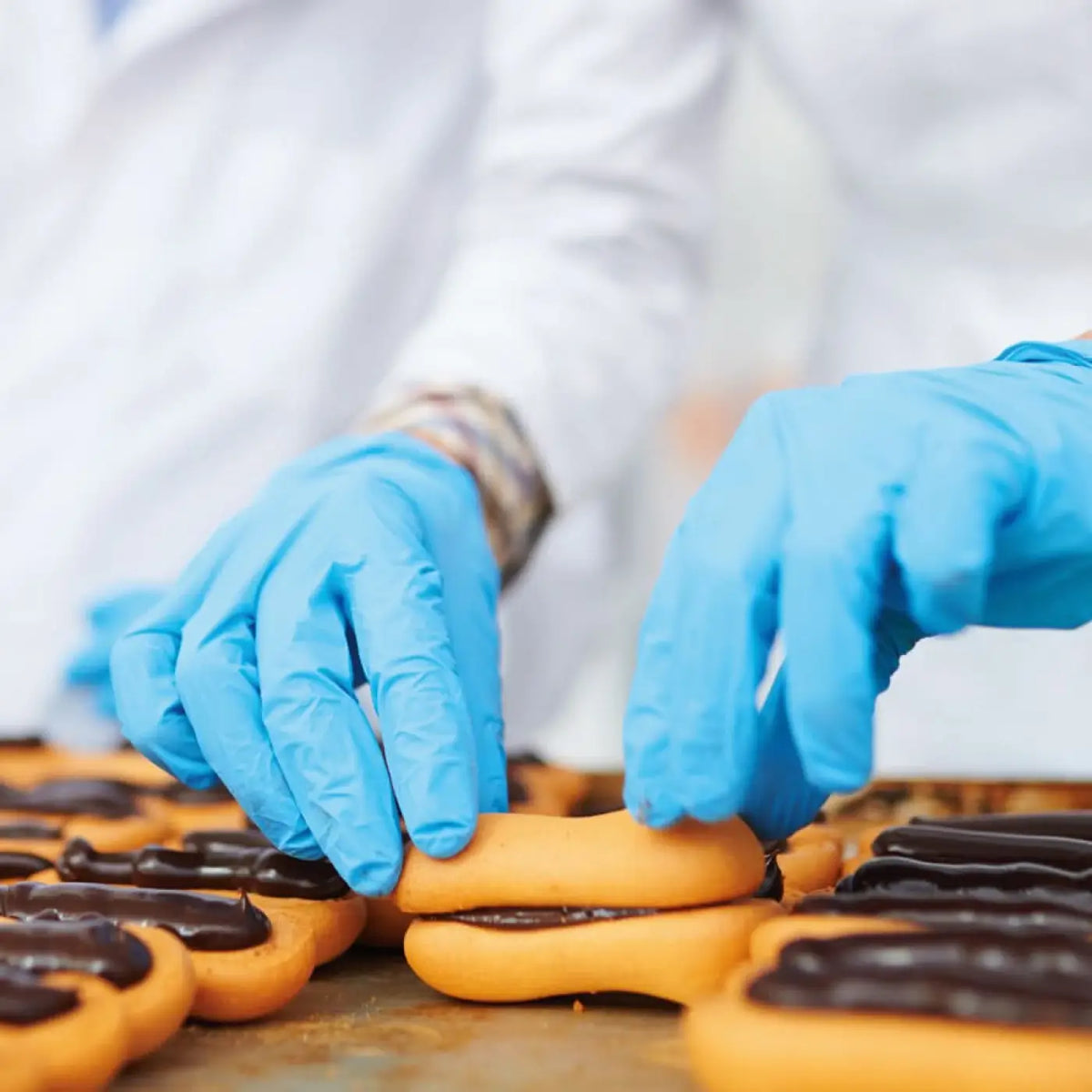 HygoStar nitrilhandschuhe extra safe blau puderfrei werden zum handling von goldbraunen schokogefüllten gebäckstücken verwendet