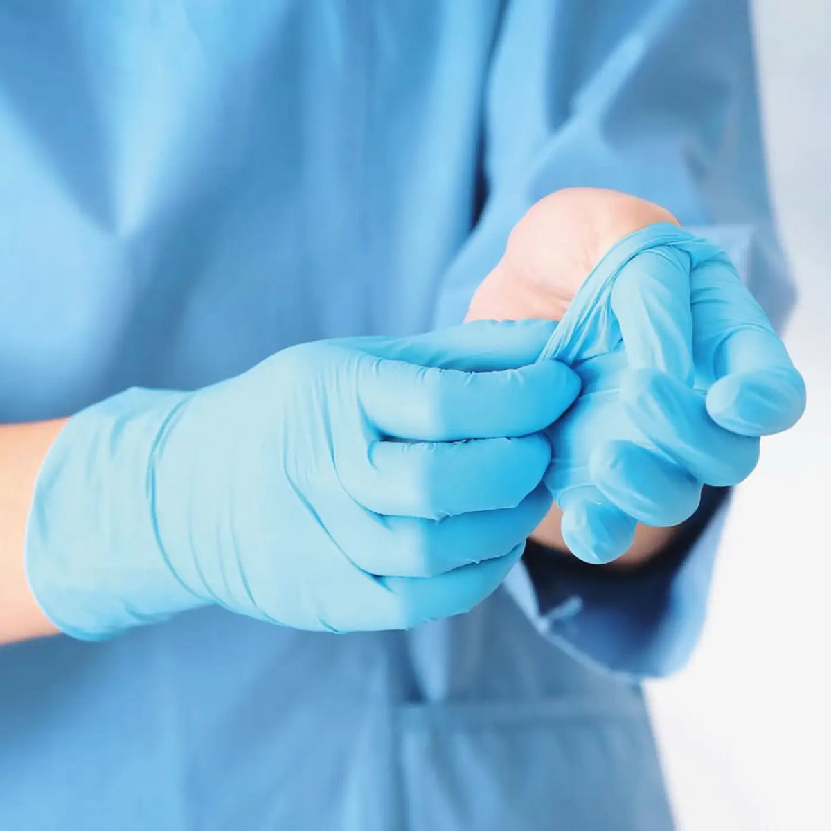 Hands wearing light blue nitrile medical gloves from hygostar safe light 100 pieces pack