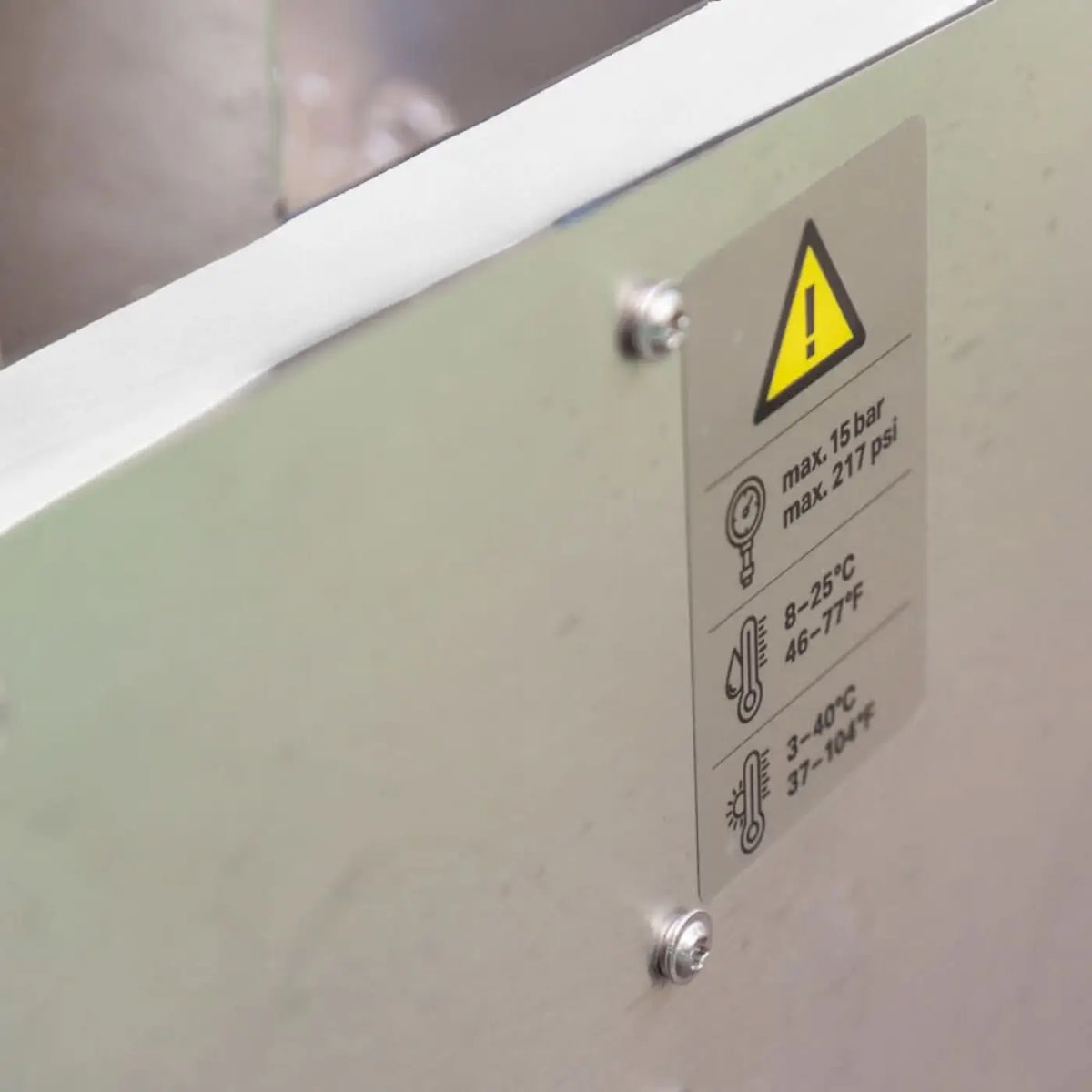 Ein metallisches warnschild mit gelbem dreieckigem vorsichtssymbol und schwarzem text zur maximaldruck- und temperaturangabe der osmobil max 750 liter osmoseanlage für pv solar glas und fassade