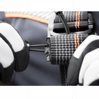 Skylotec ignite trion sicherheitsgurt mit schwarz orange kariertem gurtband und schwarzer metallschnalle wird von hand mit handschuh eingestellt