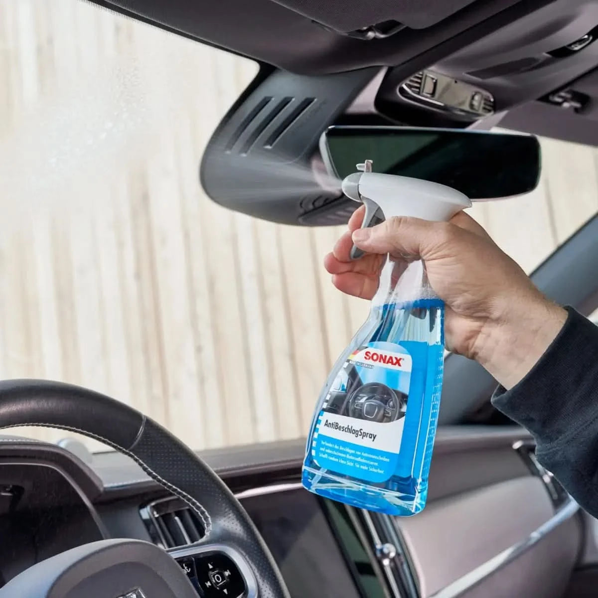 Ein transparenter blauer sprayflasche mit weißem abzug und etikett sonax antibeschlagspray für autoinnenverglasung