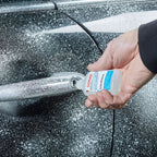 A clear plastic bottle with a white cap and blue sonax schlossentester label held by a hand for lock de-icing