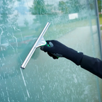 Unger ergotec glasreinigungshandschuhe mit silberner gummilippe und grün schwarzem ergonomischem griff am glas genutzt