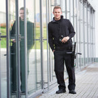 Schwarze ungler ergotec ninja 6in1 taktische weste mit reißverschluss und taschen über schwarzer jacke getragen